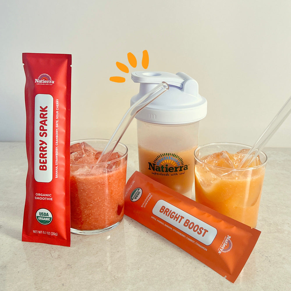 Berry Spark and Bright Boost smoothie packets in a glass and shaker