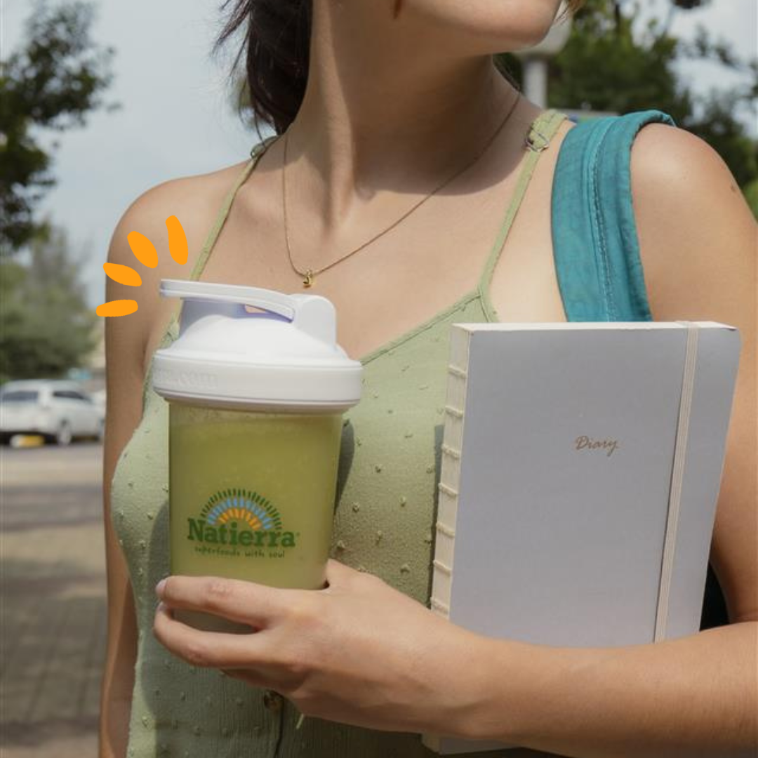 Girl holding a notebook in one arm and a smoothie in one hand