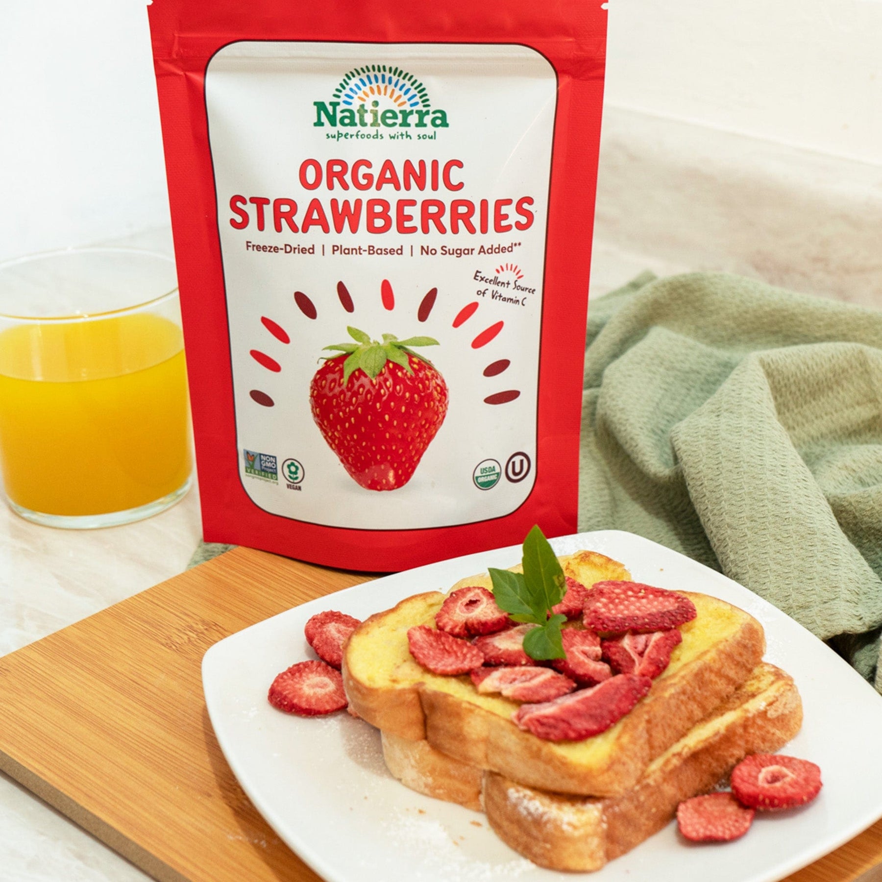 A plate of french toast topped with Natierra Organic Freeze-Dried Strawberries and a glass of orange juice