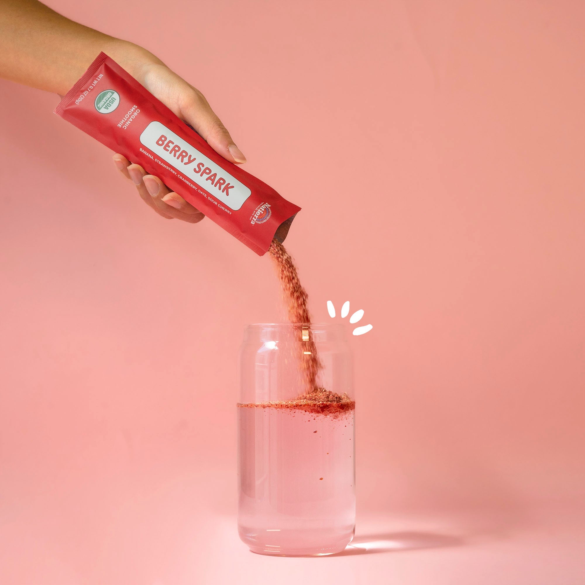 Natierra's Berry Spark smoothie powder pouring into a glass of water