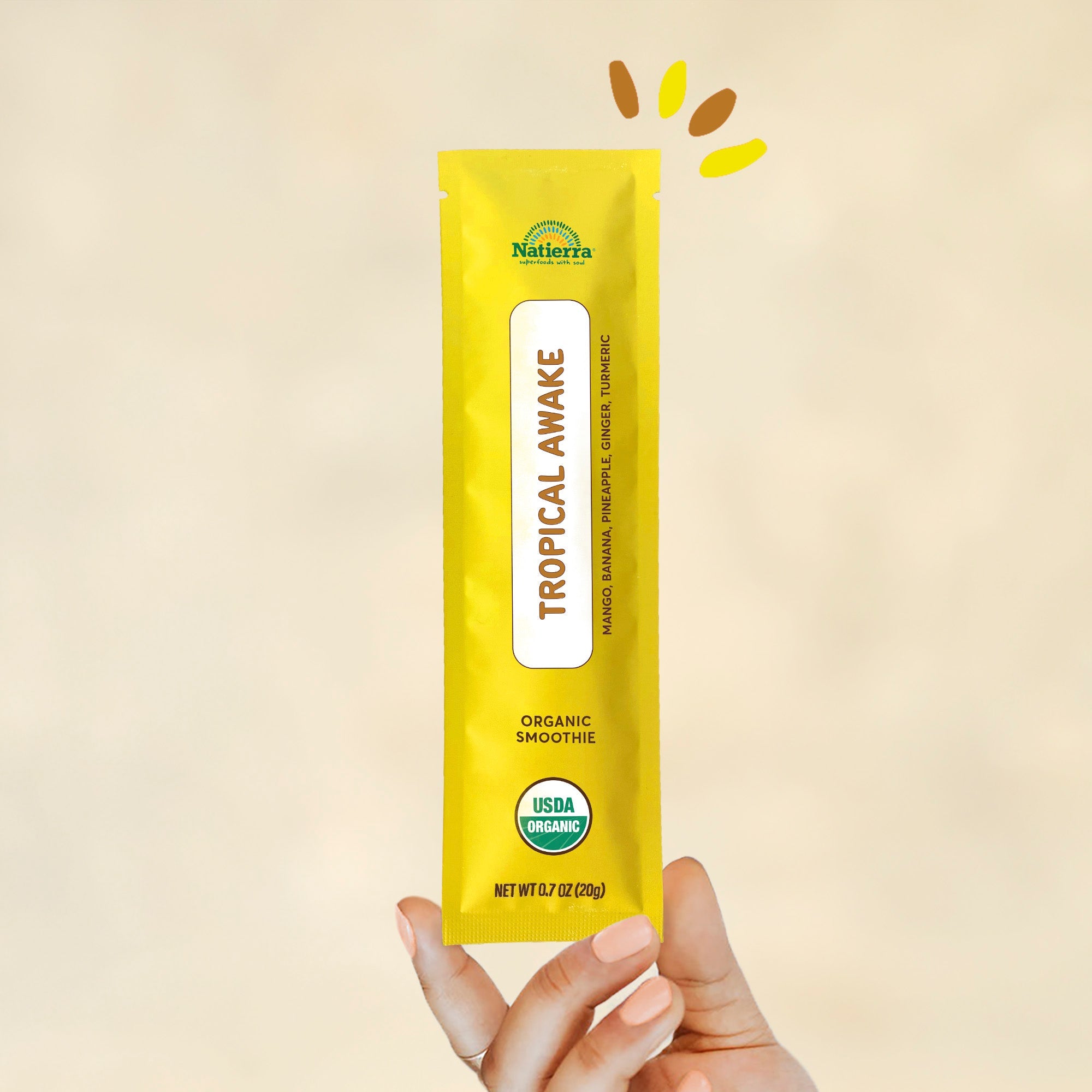 Organic Tropical Awake smoothie powder blend packet hold by a hand