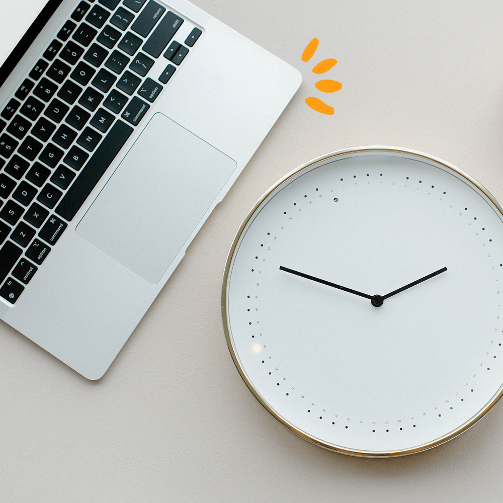 Laptop next to a round clock