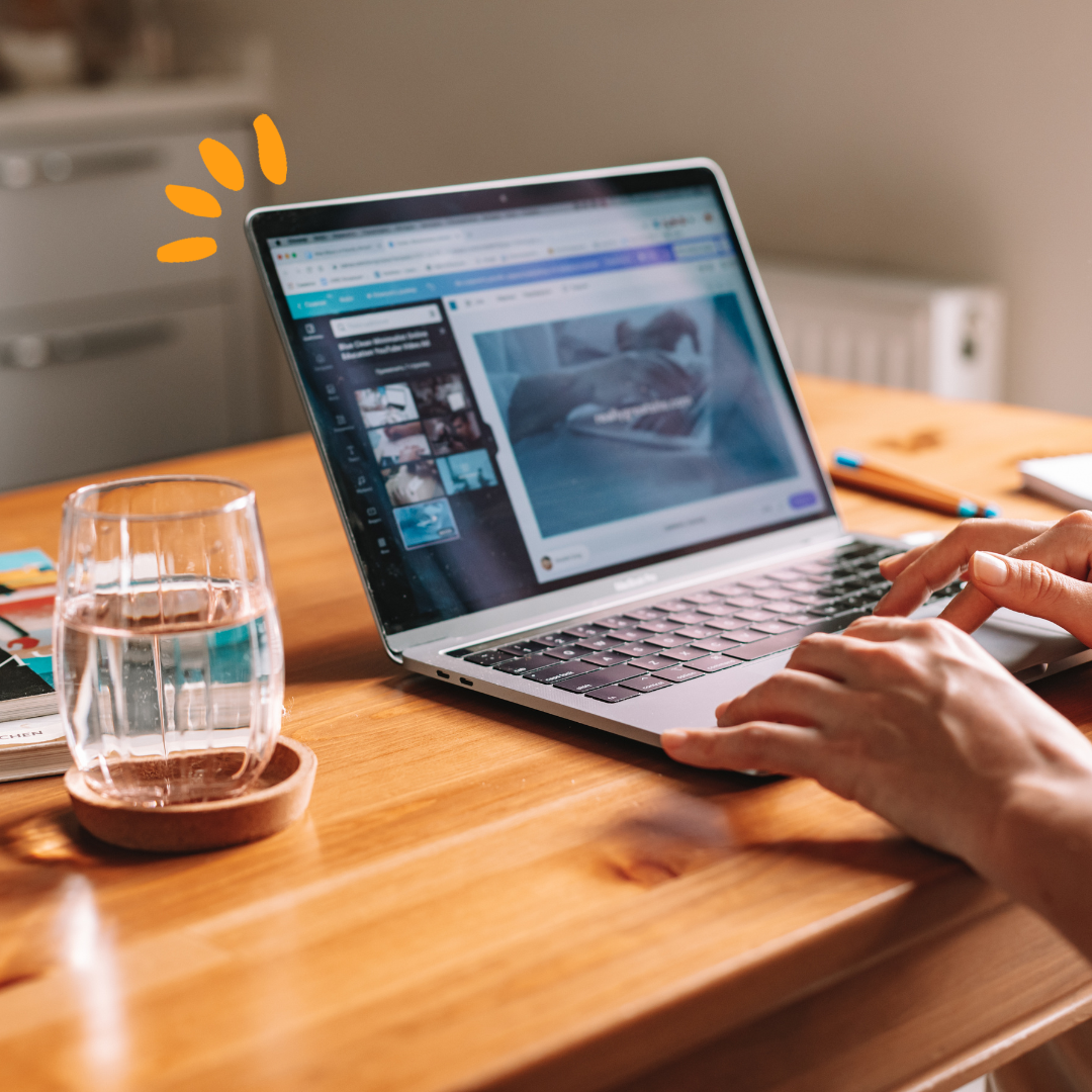 Laptop on a desk next to a glass of water