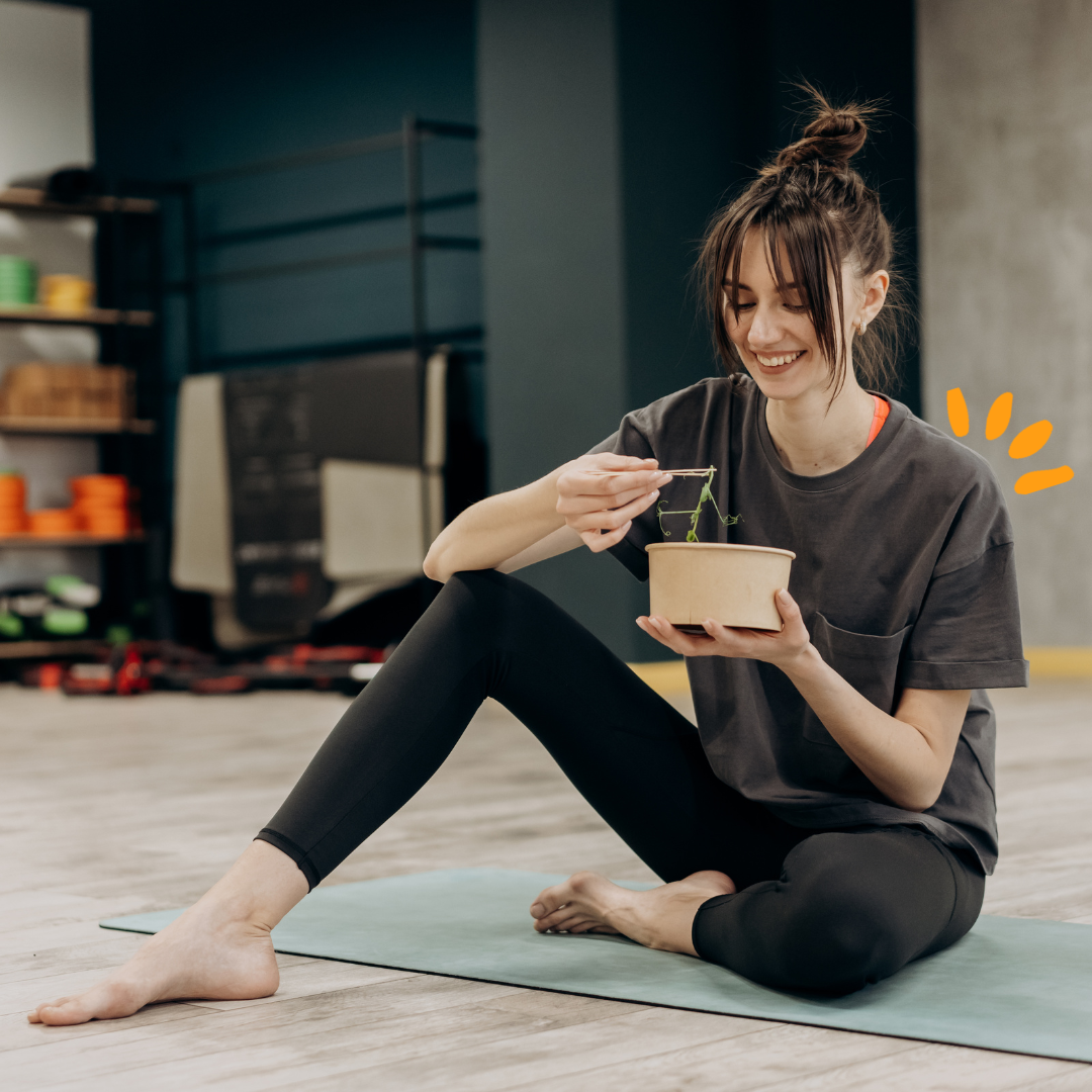 Woman sitting on the floor eating at the gym