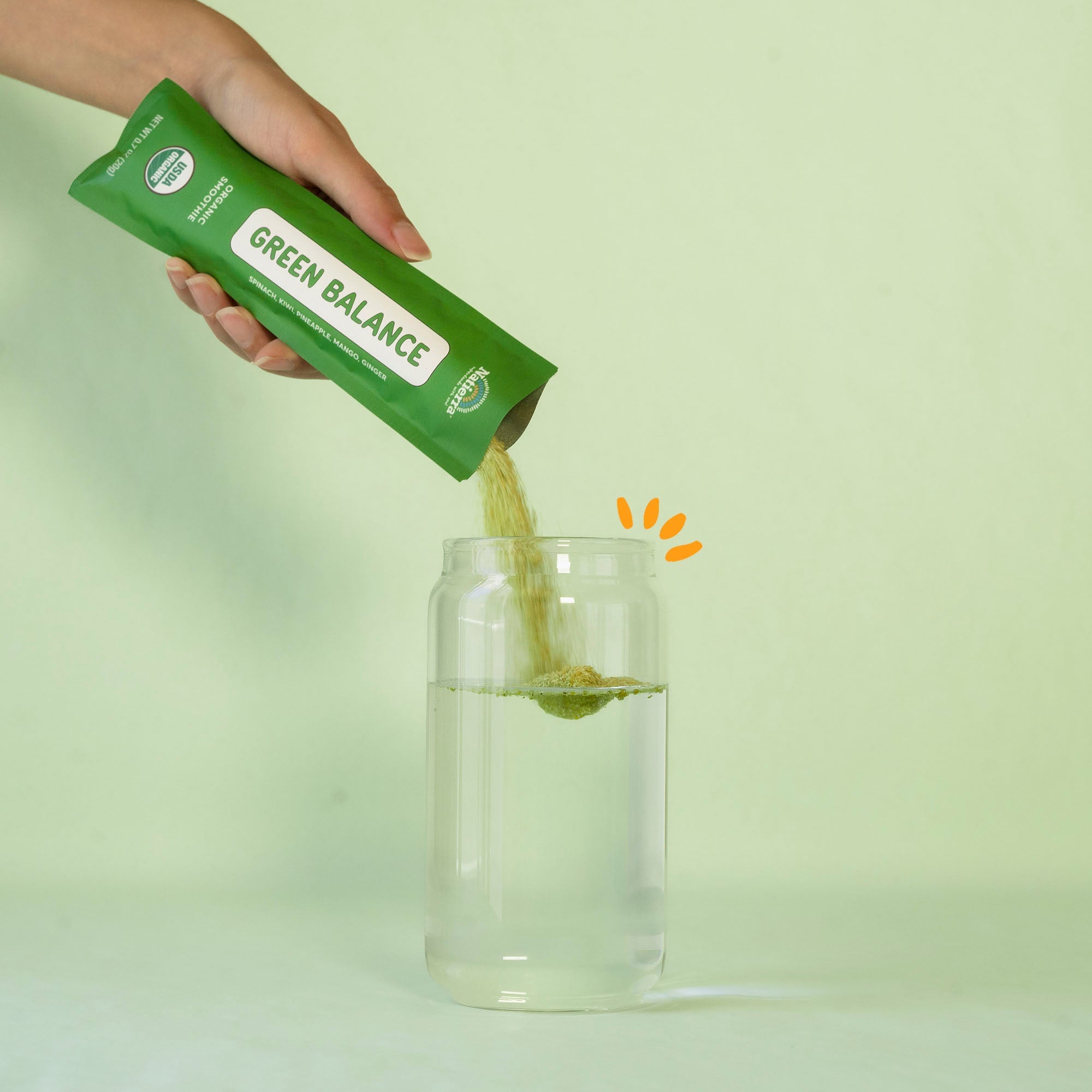 Person pouring Green Balance smoothie powder into a glass of water