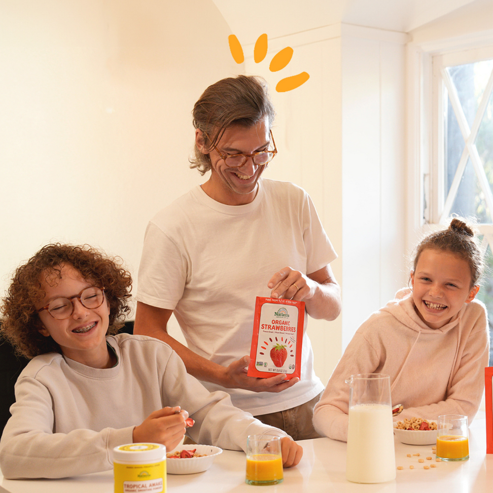 Two kids and one adult having fun in the kitchen while eating organic freeze-dried fruits and drinking organic smoothies