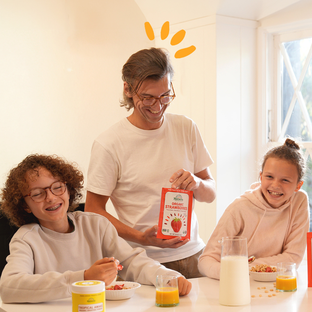 Two kids and one adult having fun in the kitchen while eating organic freeze-dried fruits and drinking organic smoothies