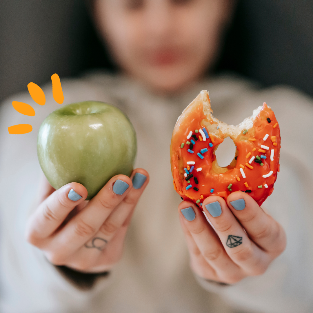 A women holding one fresh apple in one hand and a donut in the other