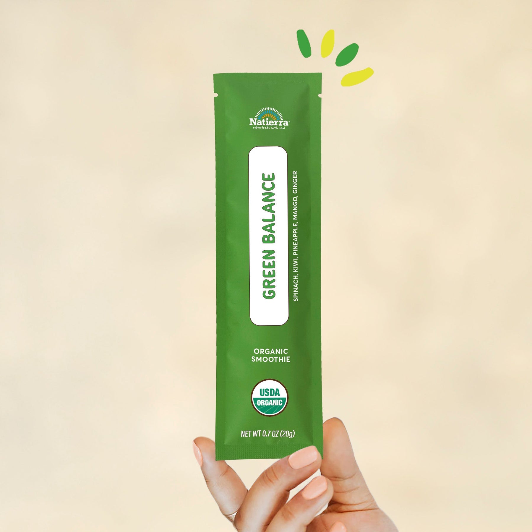 Individual stick pack of Natierra's Green Balance Organic Smoothie held by a hand in front of a creme background